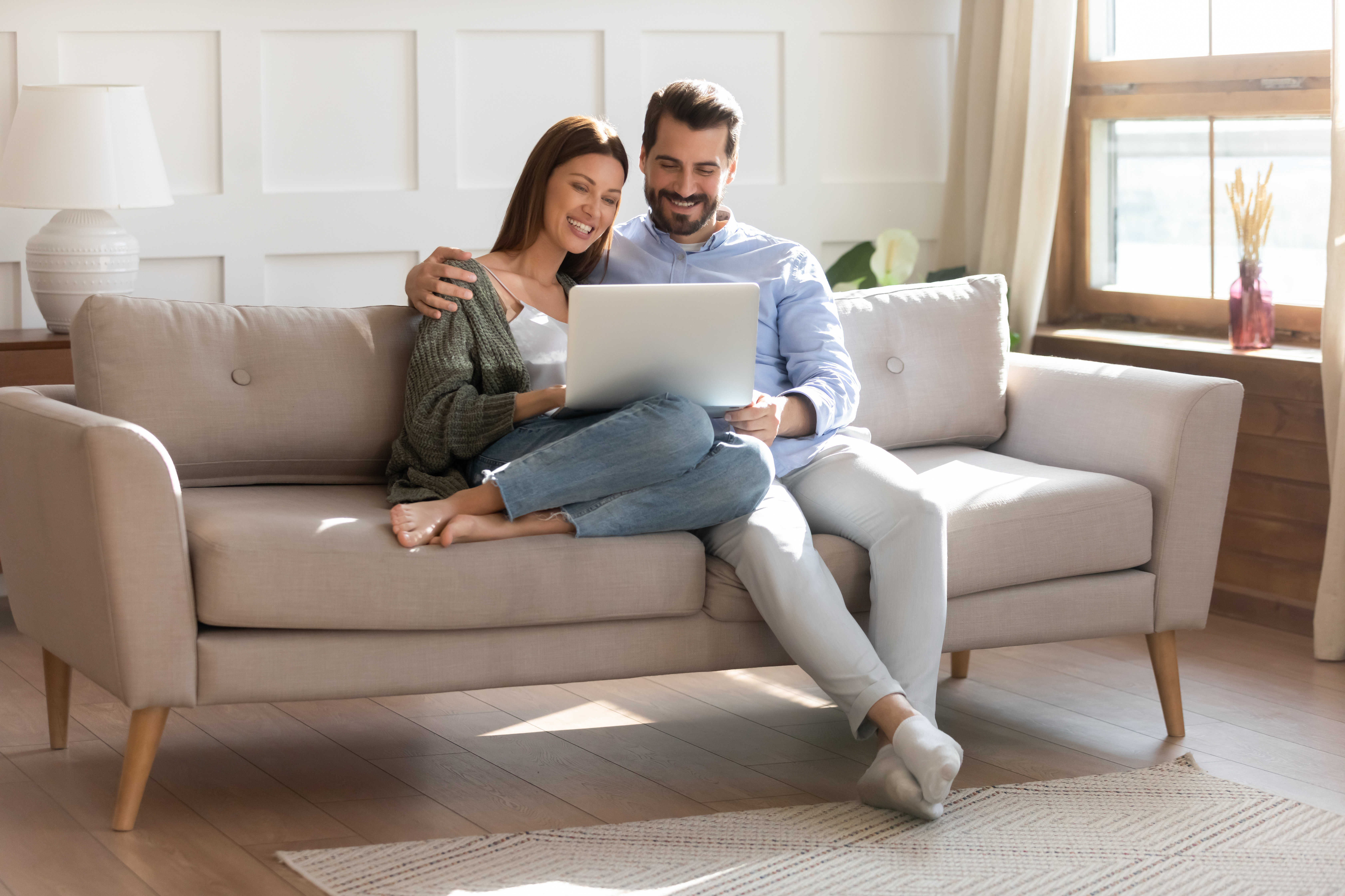 Happy male and female couple search listings on a laptop