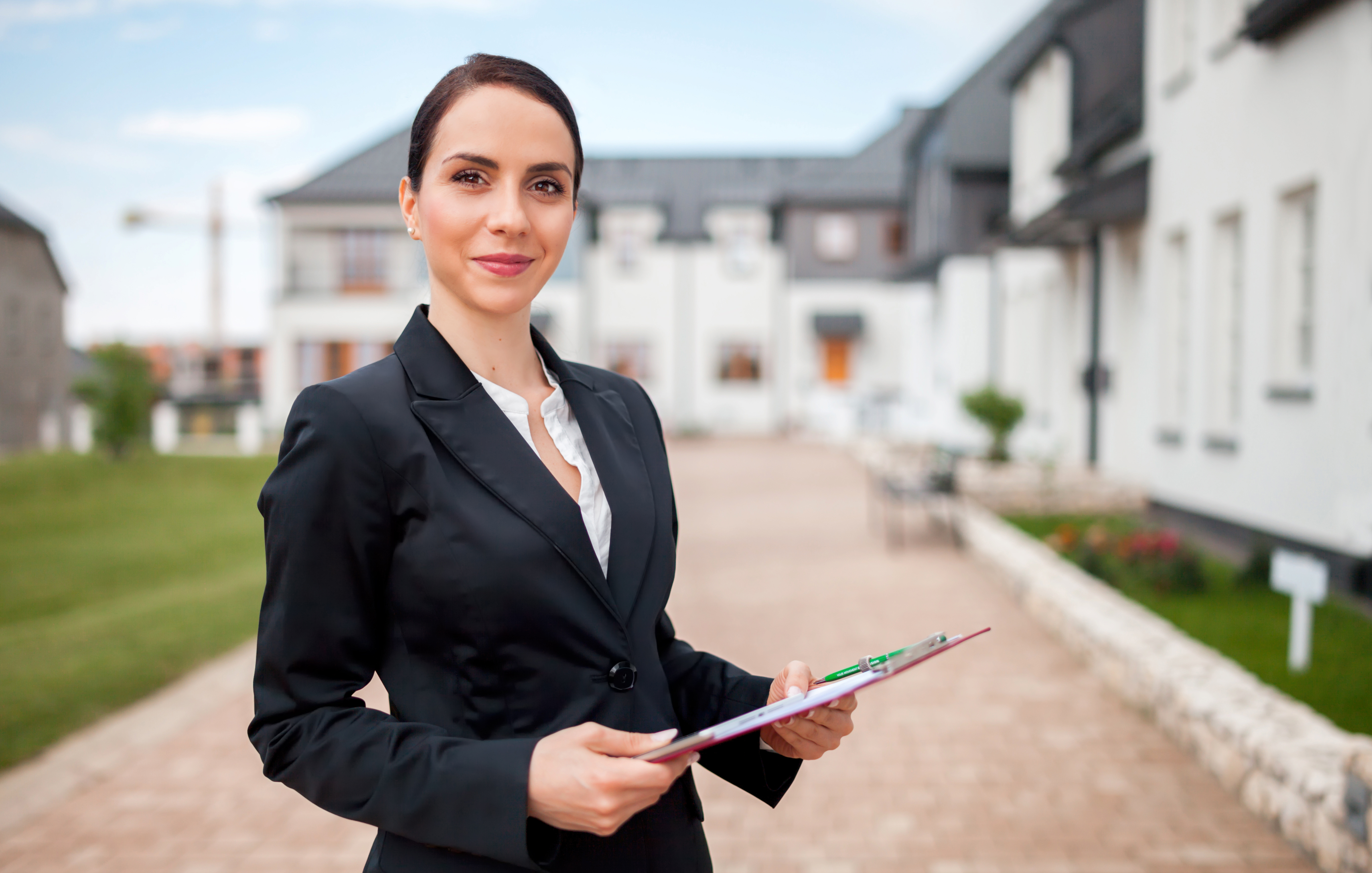 Brunette female property manager in business suit holds a clipboard